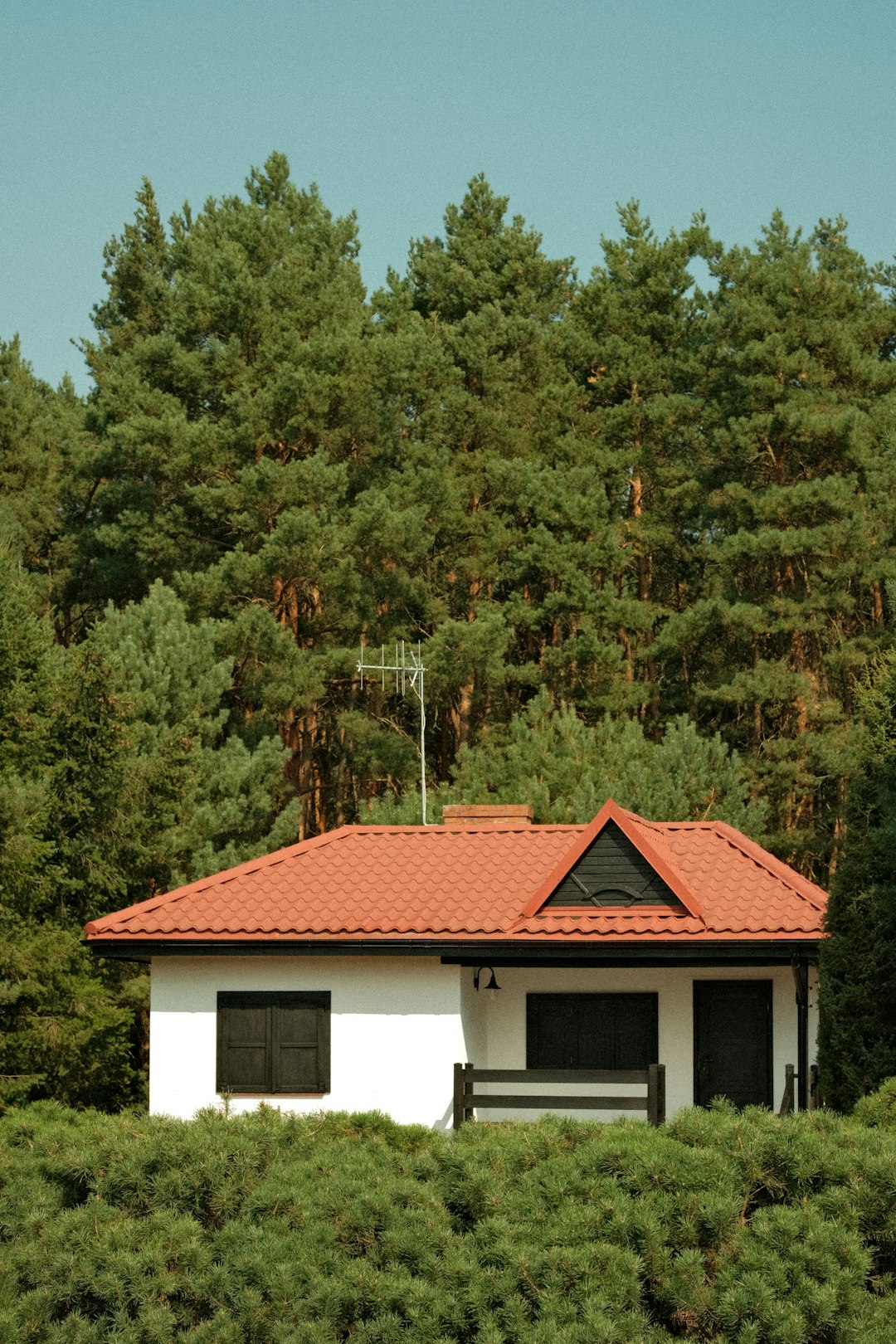 a-white-house-with-a-red-roof-surrounded-by-trees-rbjo-cqu1hm